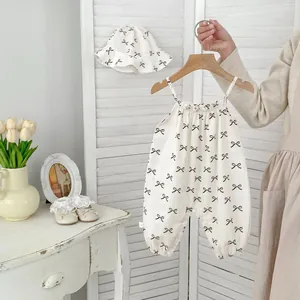 Detailed view of baby summer romper with bow pattern, matching sun hat and ruffle collar