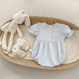 Détail d'un body bleu clair pour bébé fille avec volants et boutons au dos sur un panier