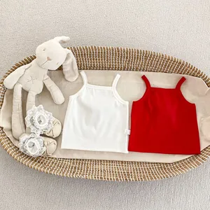 Detail of ribbed cotton baby tank tops and lace shoes in a cozy basket setting