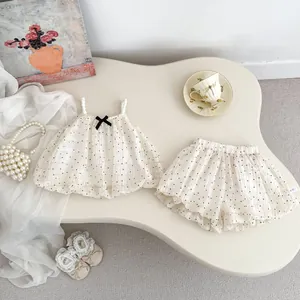 Polka dot baby girl summer set with pearl straps and black bow accent on white fabric