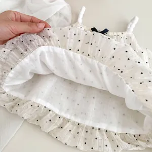 Detail of polka dot top featuring ruffled edges, woven straps and a black bow accent