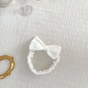 Gros plan d'un bandeau à nœud en coton blanc texturé pour bébé fille avec décor doré