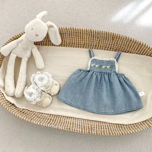 Close-up of light blue denim baby top with flower embroidery and lace detailing