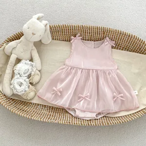 Detail of pink baby bodysuit with bow accents and soft tulle skirt in a nursery setting