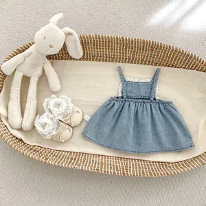 Detail of baby denim dress with white lace trim and bow shoes in a woven basket