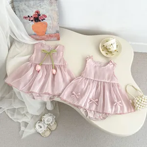 Detail of pink satin baby rompers with delicate bow accents and tulip floral pendant