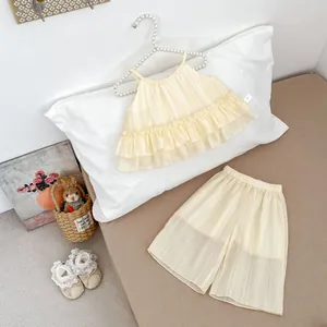 Détail d'un ensemble d'été pour bébé fille avec haut à volants et short large en crème
