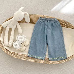 Detail of baby girl denim pants featuring floral embroidery and elastic waistband in a basket