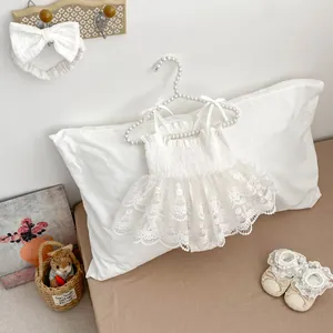 Détail de la robe de bébé en tulle et dentelle blanche avec bandeau et chaussons fleuris