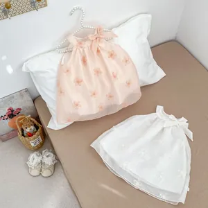 Dettaglio vestito senza maniche neonata con ricamo floreale e fiocco su gruccia di perle