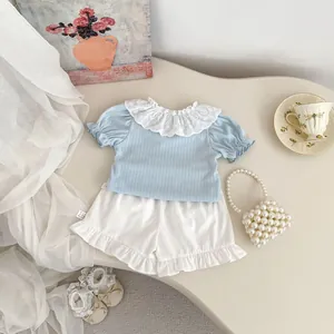 Detail of light blue baby girl outfit with lace collar and white ruffled hem shorts