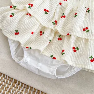 Detail of baby cherry print dress showing ruffled hem and convenient snap buttons at bottom