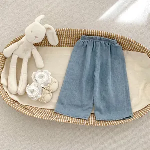 Flat lay of baby light blue denim wide leg pants with elastic waist and lace shoes