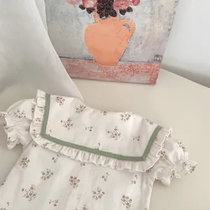 Detalle de blusa floral para bebé con cuello marinero de volantes y ribete verde
