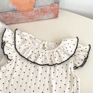 Detail von Baby Mädchen gepunktetes ärmelloses Top mit Rüschenkragen und Kontrastrand