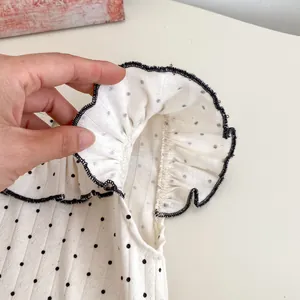 Detail von Babymädchen-Sommeroberteil mit weißen Polka-Dots, Rippstrick und Rüschenkanten