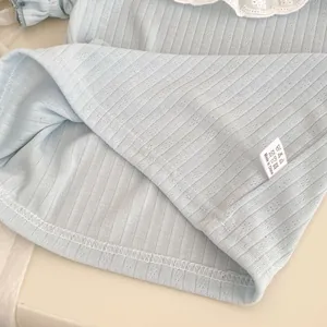 Close-up of light blue ribbed fabric with white lace collar and garment wash label