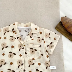 Dettaglio ravvicinato della maglietta beige per bambini con stampe di cuccioli e biscotti