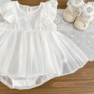 Detail of white embroidered baby tulle romper dress with snap buttons and lace shoes