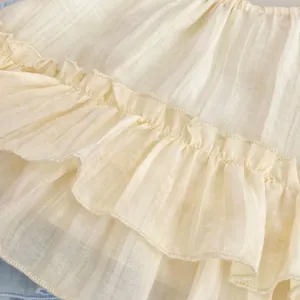 Détail macro du tissu à rayures crème respirant et des volants sur ce vêtement d'été