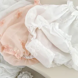 Detail of floral embroidery and ruffled edge on soft cotton baby bodysuit rompers