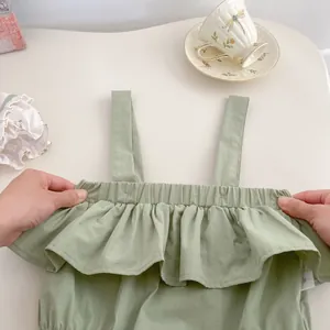 Detalle del escote elástico y volantes en el body de algodón verde para bebé niña
