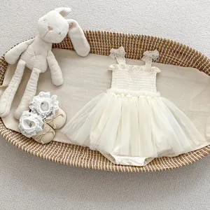 Detail of cream tulle baby bodysuit dress and lace shoes with a plush bunny in a basket