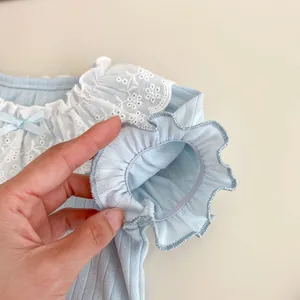Close-up of baby girl top with lace collar, floral embroidery and blue silk bow