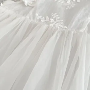 Detail of white floral embroidery on baby tulle dress with layered mesh fabric texture