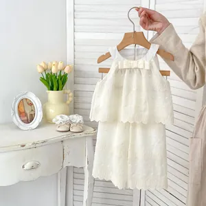 Detail of white cotton girls' summer set with delicate lace layers and bow on wooden hanger