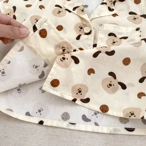 Dettaglio camicia estiva per neonato con stampe di cani carini e bottoni bianchi