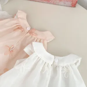 Detail of floral embroidery and button closure on pink and ivory baby rompers