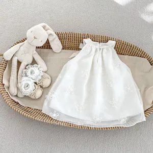 Dettaglio di un vestito da neonata con ricami floreali e scarpe con fiocco abbinate