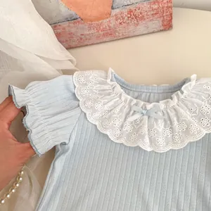 Close-up of girls blue ribbed top with lace collar and bow detail on textured background