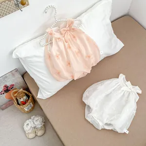 Close-up of floral embroidery and delicate bow on mesh infant bodysuit and lace shoes