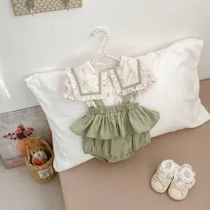 Detalle de camisa floral para bebé con cuello grande y pantalones de tirantes con volantes
