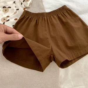 Dettaglio dei pantaloncini da bambino in cotone e lino marroni con elastico in vita e cane
