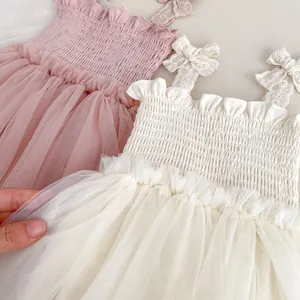 Detail of smocking chest and lace bow straps on the pink and cream tulle baby dresses
