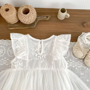 Detailed view of white floral mesh baby dress with matching lace newborn shoes