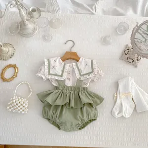 Plano detalle de camisa floral para bebé y pelele verde con accesorios decorativos vintage