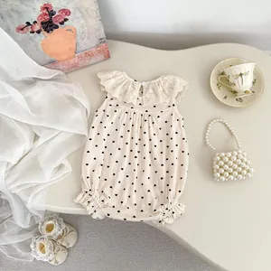 Détail de la barboteuse bébé sans manches avec col en dentelle et motif de cœur noir
