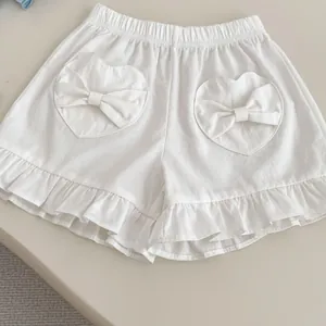 Close-up of white cotton girls shorts with heart-shaped pockets and bow details