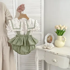 Detalle de camisa floral para bebé con cuello grande y pantalón de tirantes verde