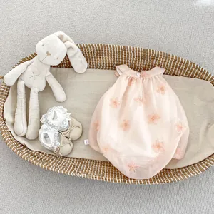 Detail of pink floral embroidered baby romper and lace socks in a woven basket