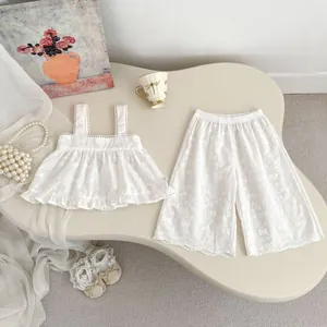 Détail d'un ensemble blanc brodé pour bébés avec haut à bretelles et pantalon large