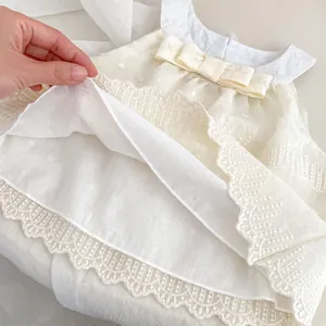 Detailed close-up of multi-layer lace dress hem with satin bow and delicate stitching