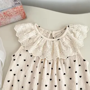 Détail d'une barboteuse bébé beige à motifs cœurs et col en dentelle brodée de fleurs