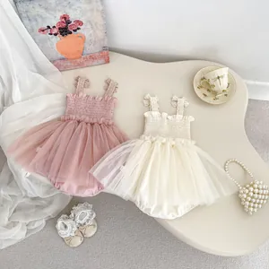 Flat lay of pink and beige tulle baby rompers with lace straps and elegant mesh skirt