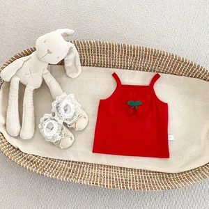 Detail of red cherry baby vest with 3D applique on ribbed cotton fabric in a basket