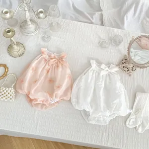 Detailed embroidery and bow accents on French style baby rompers with elegant accessories